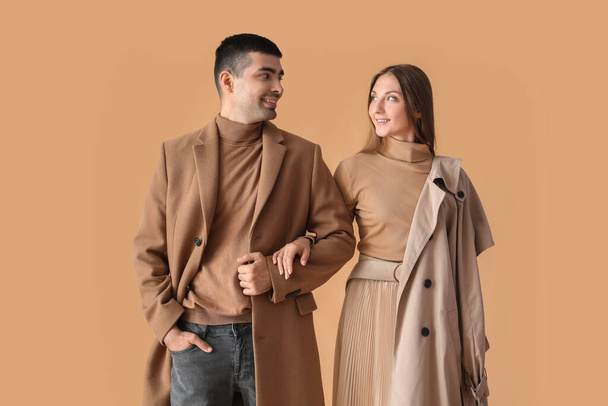 Fashionable young couple in autumn clothes on beige background - Valokuva, kuva