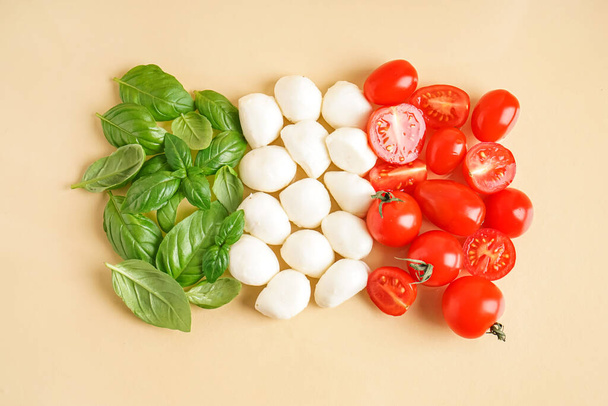 Samenstelling met heerlijke mozzarella kaas, basilicum en tomaten op kleur achtergrond - Foto, afbeelding