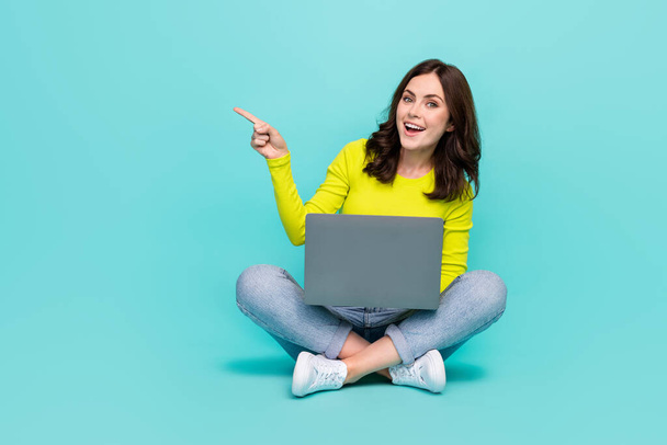 Full length portrait of excited positive person indicate finger empty space isolated on teal color background. - Фото, изображение