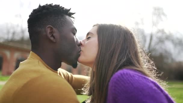 Молодая межрасовая пара целуется снаружи. Черный мужчина с белым поцелуем подруги, концепция разнообразия - Кадры, видео
