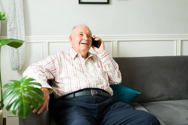 Happy vanhempi mies kotona nauraa puhuu puhelimessa perheen tai ystävien kanssa ja hauskaa rentoa aikaa  - Valokuva, kuva