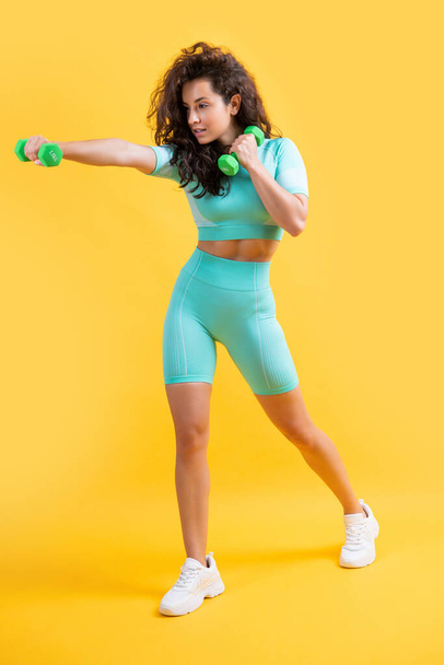 sport woman do weightlifting exercise with dumbbell, full length. sport woman do weightlifting exercise isolated on yellow background. fitness and sport. - Fotografie, Obrázek