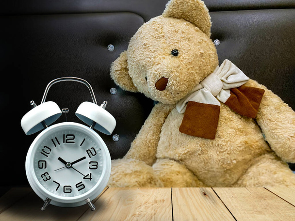 Brauner Teddybär schläft im Bett mit Wecker - Foto, Bild
