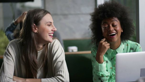 Různé ženy v kavárně v konverzaci. Tři skupiny přítelkyň sedících v kavárně se smějícím se laptopem - Fotografie, Obrázek