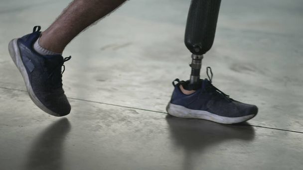 Людина з обмеженими можливостями ходить з протезом ноги в приміщенні. Чоловік з ампутованими кінцівками ходить з протезом
 - Фото, зображення