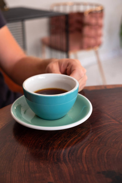 Мужчина, сидящий за столом в кафе и пьющий чашку кофе. - Фото, изображение