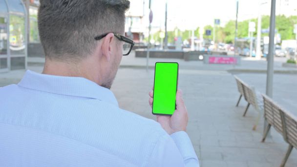 Hombre de mediana edad usando Smartphone con pantalla verde al aire libre - Foto, Imagen