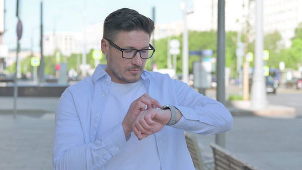 Középkorú férfi Böngészés Internet a Smartwatch Outdoor - Fotó, kép
