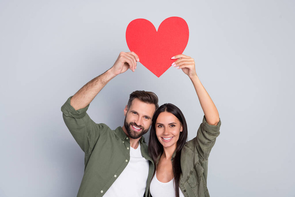 Portrait of attractive cheerful couple hugging holding heart card shape form cupid isolated over grey pastel color background. - Fotoğraf, Görsel