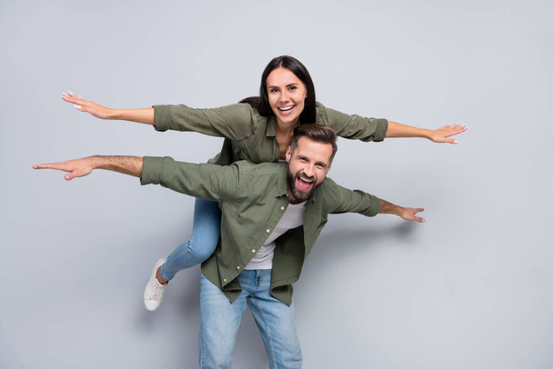 Portrait of attractive cheerful trendy couple friends piggy backing having fun isolated over grey pastel color background. - Фото, изображение
