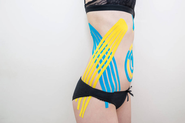 kinesio tape on the sides of the abdomen of a young girl. - Фото, зображення