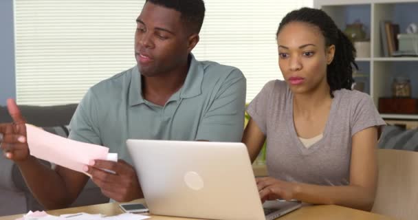Vážný mladý černý pár platit účty online s přenosným počítačem - Záběry, video