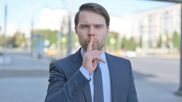 Outdoor Portrait of Businessman with Finger on Lips, Please be Quiet - Photo, image
