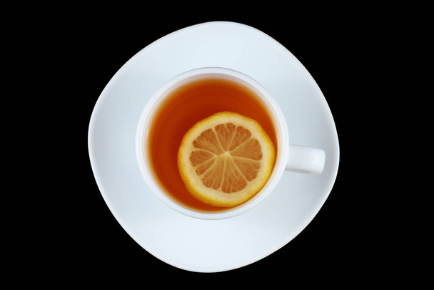 白いカップにレモンとお茶。黒を基調としたお茶 - 写真・画像
