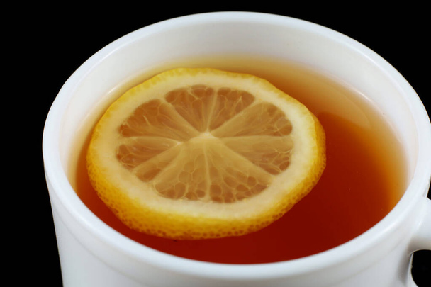 Beyaz bardakta limonlu çay. Siyah arkaplanda çay - Fotoğraf, Görsel