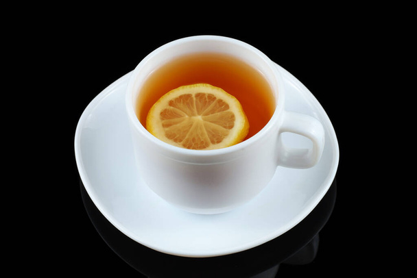 Tea with lemon in a white cup. Tea on a black background - Photo, Image