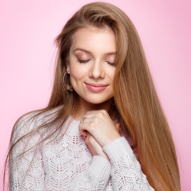 Pretty young woman with her eyes closed smiling at the pink background. - Fotografie, Obrázek