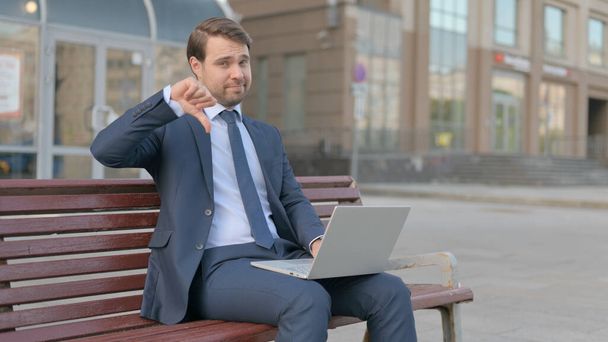 Thumbs Down by Young Businessman with Laptop Sitting on Bench  - Photo, Image