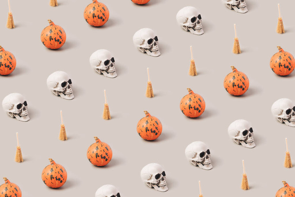 Crânios, abóboras e vassouras bruxas padrão em um fundo cinza. Halloween conceito mínimo. - Foto, Imagem