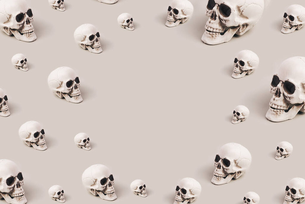 Schedels in verschillende maten gerangschikt op een grijze achtergrond. Spookachtige Halloween kopieerruimte - Foto, afbeelding