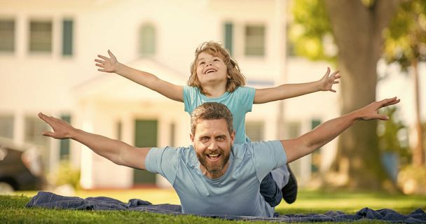 parent relax with small child boy on grass. dad with kid on summer day. parenting and fatherhood. fathers day. happy father and son having fun in park. family value. childhood and parenthood. - Photo, Image