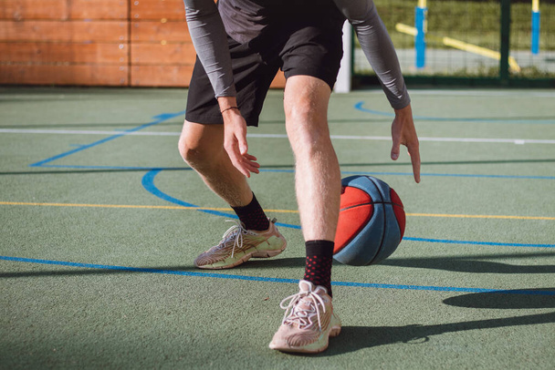 Young talent practices dribbling the basketball under his feet and improves his hand, body and foot coordination. Basketball game. Learning the trick, the deception. - Foto, imagen