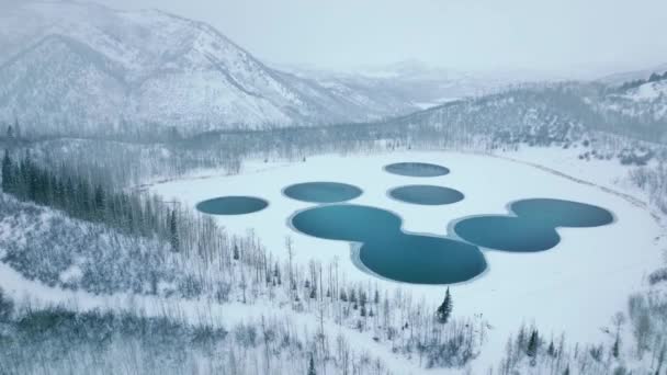 コロラド州冬のアスペンとスノーマス村の周りの水の池。曇りの寒い冬の日に完璧な円形の形で凍結されていない水湖の空中ビュー。山の工業用地 - 映像、動画