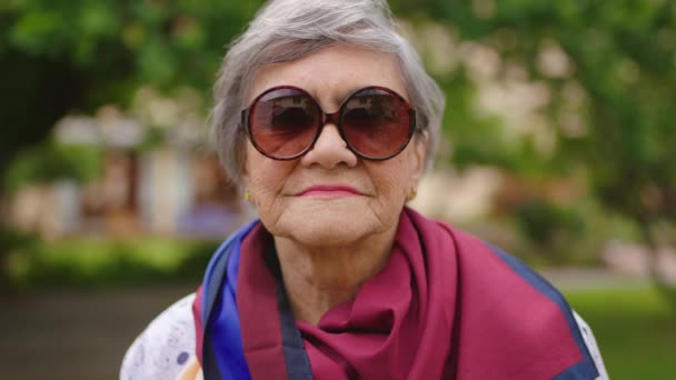 Nevető idős nő, portré és vicces mosoly, boldogság és szabadság a parkban, kertben vagy kertben nyugdíjas otthon szabadban. Menő divat, izgatott és boldog nagymama, napszemüveg és idős arc. - Felvétel, videó