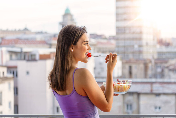 Healthy lifestyle woman eating salad smiling happy outdoors on beautiful day. Young female eating healthy food outside in summer day laughing and relaxing. - Fotoğraf, Görsel