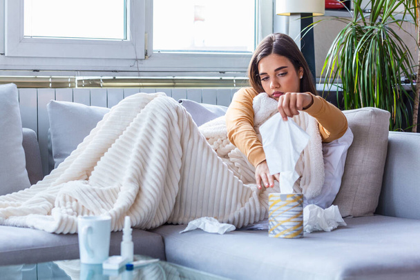 Sick Woman.Flu.Woman Caught Cold. Sneezing into Tissue. Headache. Virus .Medicines. Young Woman Infected With Cold Blowing Her Nose In Handkerchief. Sick woman with a headache sitting on a sofa - Foto, afbeelding