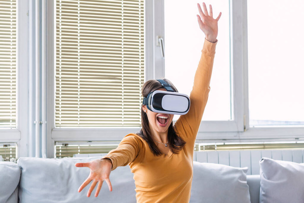 Ez annyira valóságos! Vonzó nő állítsa be a VR headsetet és mosolyogjon, miközben otthon ül a szőnyegen. VR szemüveg. 360 fok. Virtuális valóság headset. VR meccs. Virtuális valóság szemüveg viselése. - Fotó, kép