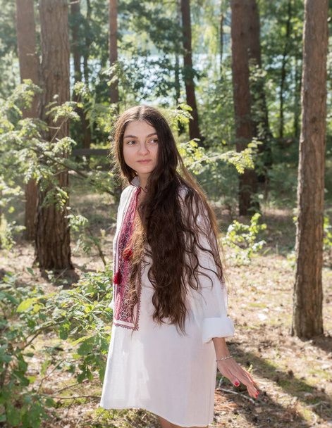 Lang haar Oekraïense meisje in een geborduurd nationaal shirt in het bos - Foto, afbeelding