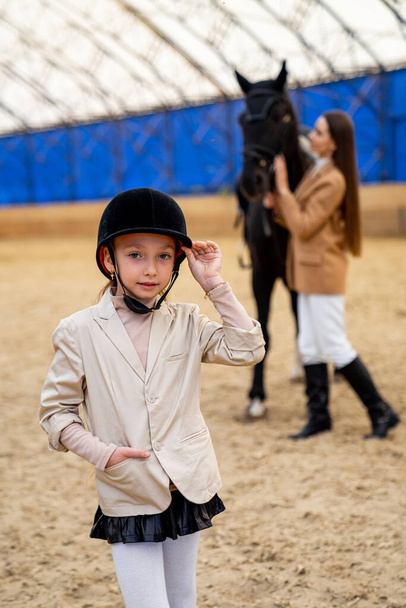 Cute girl training horse riding. Beautiful girl outdoor activity. - Foto, afbeelding