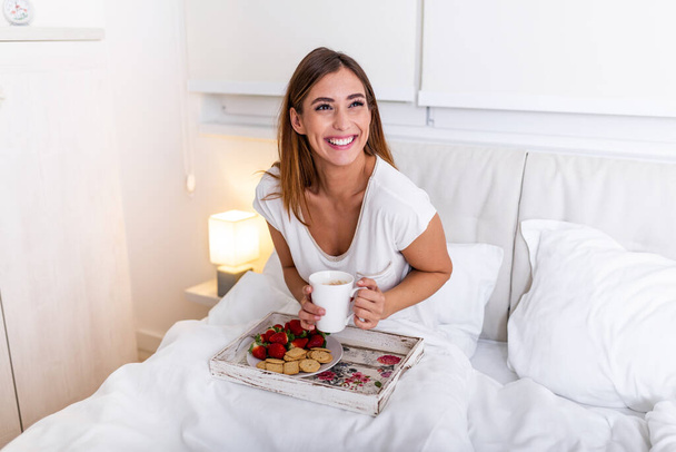 Glückliche attraktive Frau wachte morgens im Bett auf. Guten Morgen und frisches und schönes Frühstück für das Mädchen - Foto, Bild