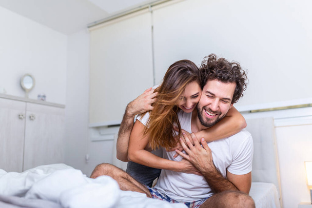 Beautiful young couple at home. Hugging, kissing and enjoying spending time together. Passionate beautiful couple in bedroom enjoying foreplay - Φωτογραφία, εικόνα