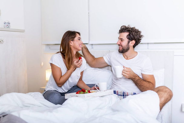 Romantic breakfast in bed man prepare for his woman, she was very happy, Young beautiful couple in bed having a breakfast and coffee in bed. Young couple having romantic breakfast in bed. - Photo, Image