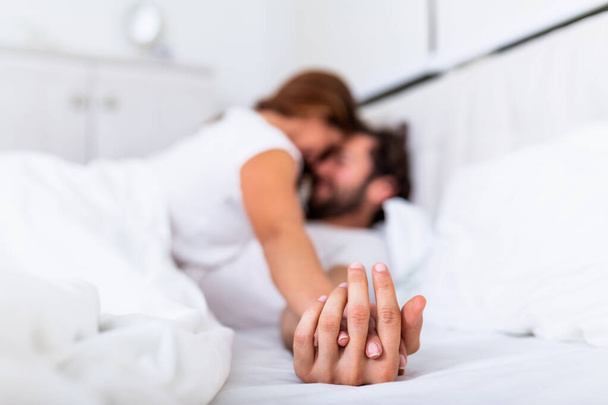 Couple romantique au lit jouissant de préliminaires sensuels. Focus sur les mains homme et femme
. - Photo, image