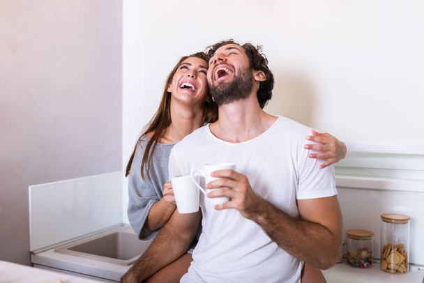 Romantic couple in love spending time together in kitchen. Cute young couple drinking coffee in kitchen and enjoying morning time together - Photo, Image