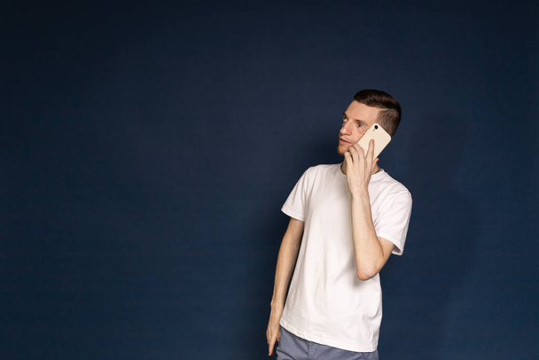 Un hombre con una camiseta blanca con síndrome de Treacher habla por teléfono - Foto, imagen