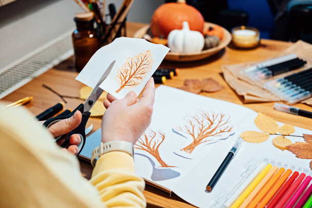 Podzimní řemeslo pro dospělé. Portrét ženy bez tváře kreslící podzimní stromy se značkami a vyřezávající koláž z papíru - Fotografie, Obrázek