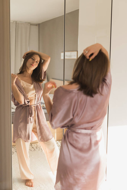 Jó reggelt! Vonzó fiatal nő tükörbe néz a lakásában.. - Fotó, kép
