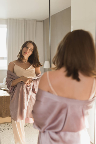 Bonne matinée. Attrayant jeune femme regardant dans un miroir à son appartement. - Photo, image