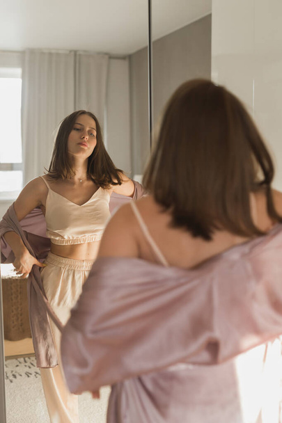 Fijne morgen. Aantrekkelijke jonge vrouw kijkt in spiegel bij haar appartement. - Foto, afbeelding