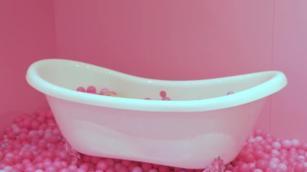 Маленькая блондинка-кавказка лежит в ванной с розовыми пластиковыми шариками. крупный план, мягкий фокус, счастливое детство. - Кадры, видео