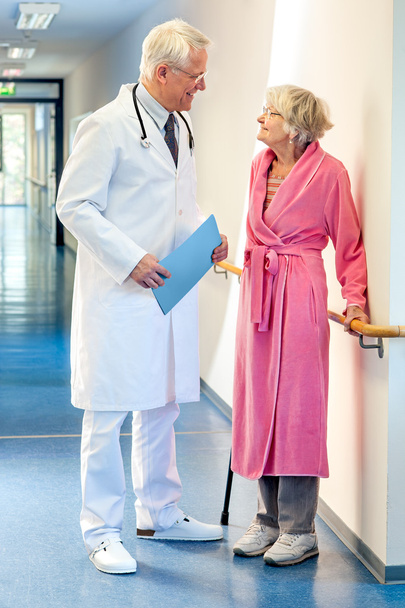 Лікар розмовляє з літньою жінкою в коридорі
.  - Фото, зображення