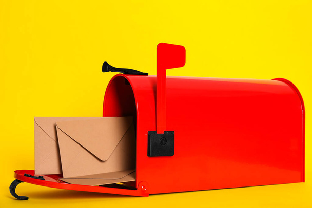 Open red letter box with envelopes on yellow background, closeup - Foto, imagen
