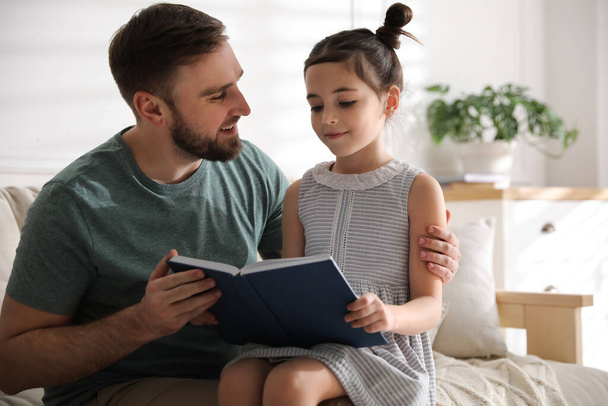 Pieni tyttö isän kanssa lukemassa satua olohuoneessa - Valokuva, kuva