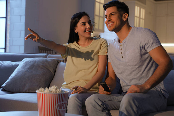 Couple watching movie with popcorn on sofa at night - Foto, afbeelding