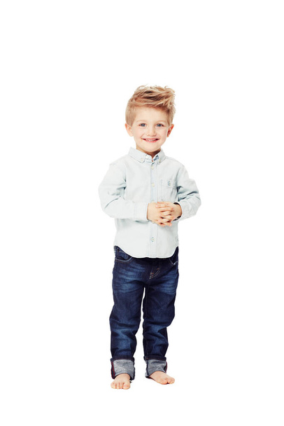 Сияющий уверенностью в своем детстве. Симпатичный маленький мальчик, смотрящий в камеру с сжатыми руками - Фото, изображение