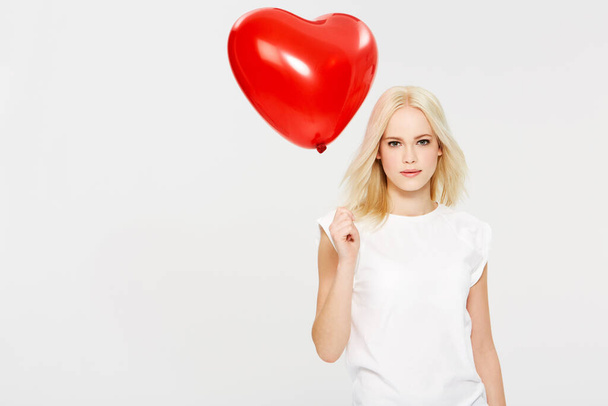 A balloon for you. A young woman holding a heart-shaped balloon against a white background - Foto, Imagem